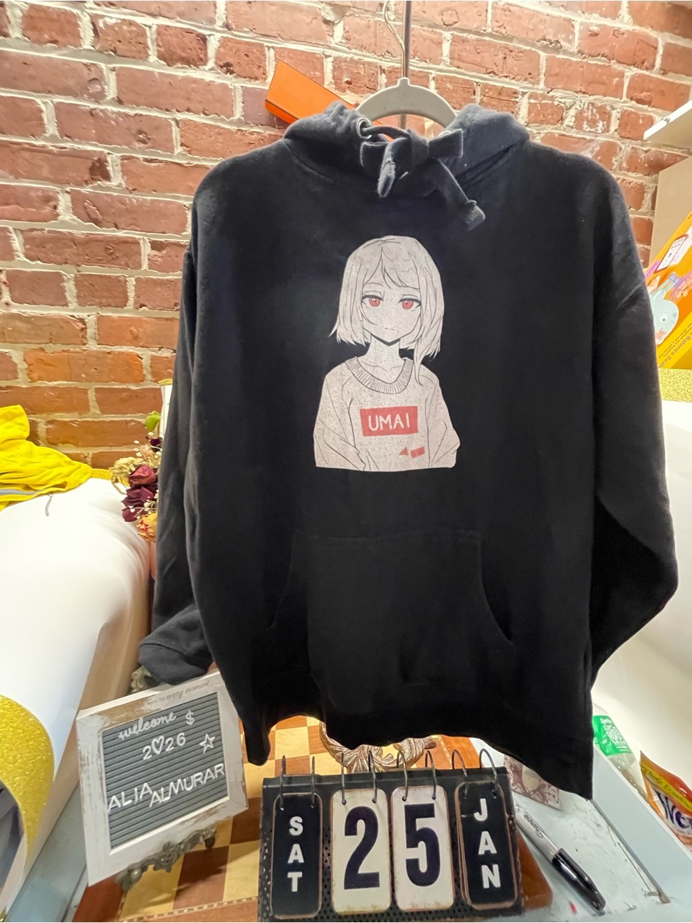 Umai Clothing hoodie features a white anime character graphic with a red rectang